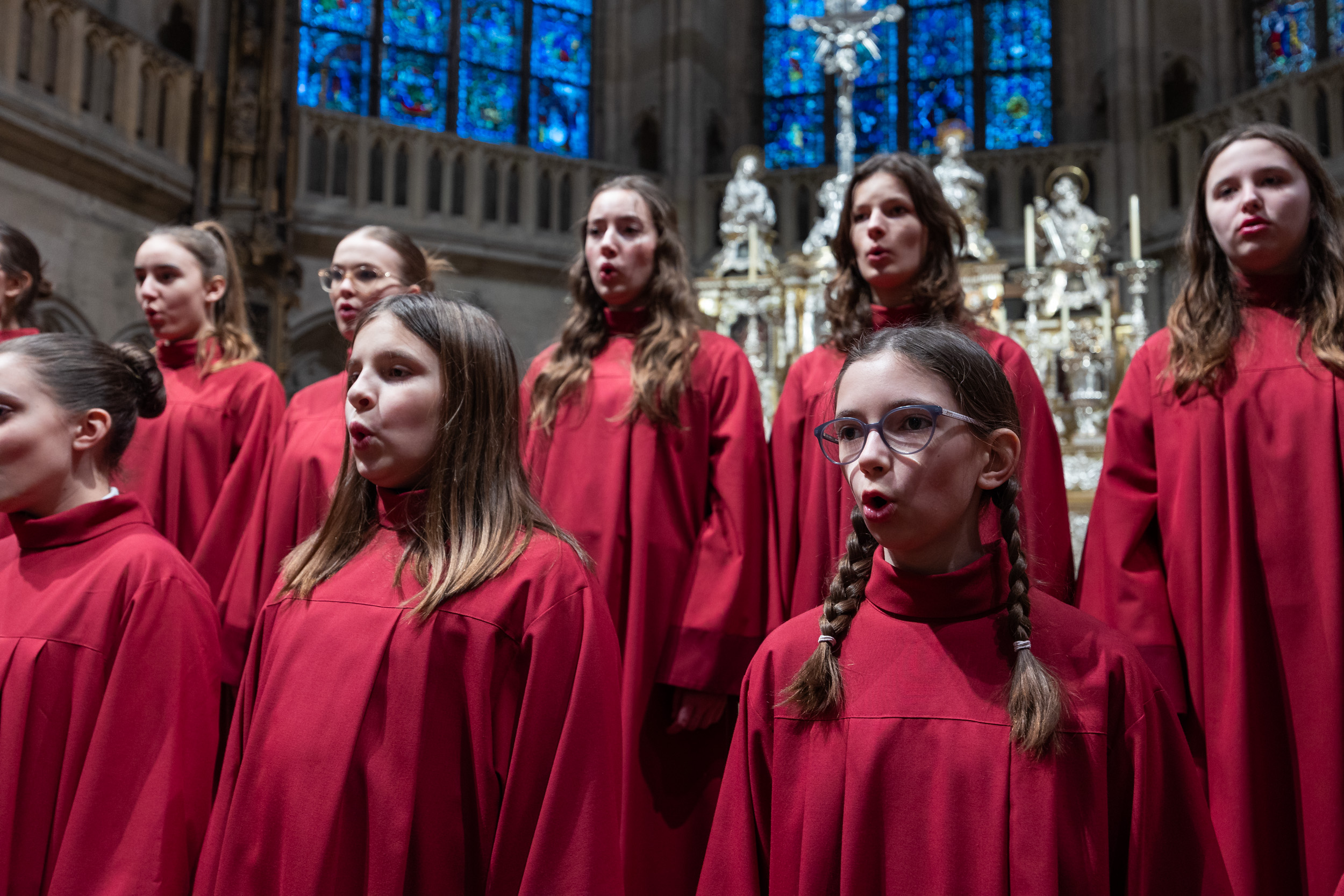 Zwei Reihen rot gewandeter Mädchen singen in abendlicher Stimmung im regensburger Dom.