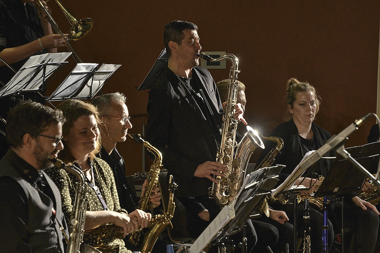 Ein Blick in die Saxophon-Section der Bigband. Ein Saxophonist steht und soliert.