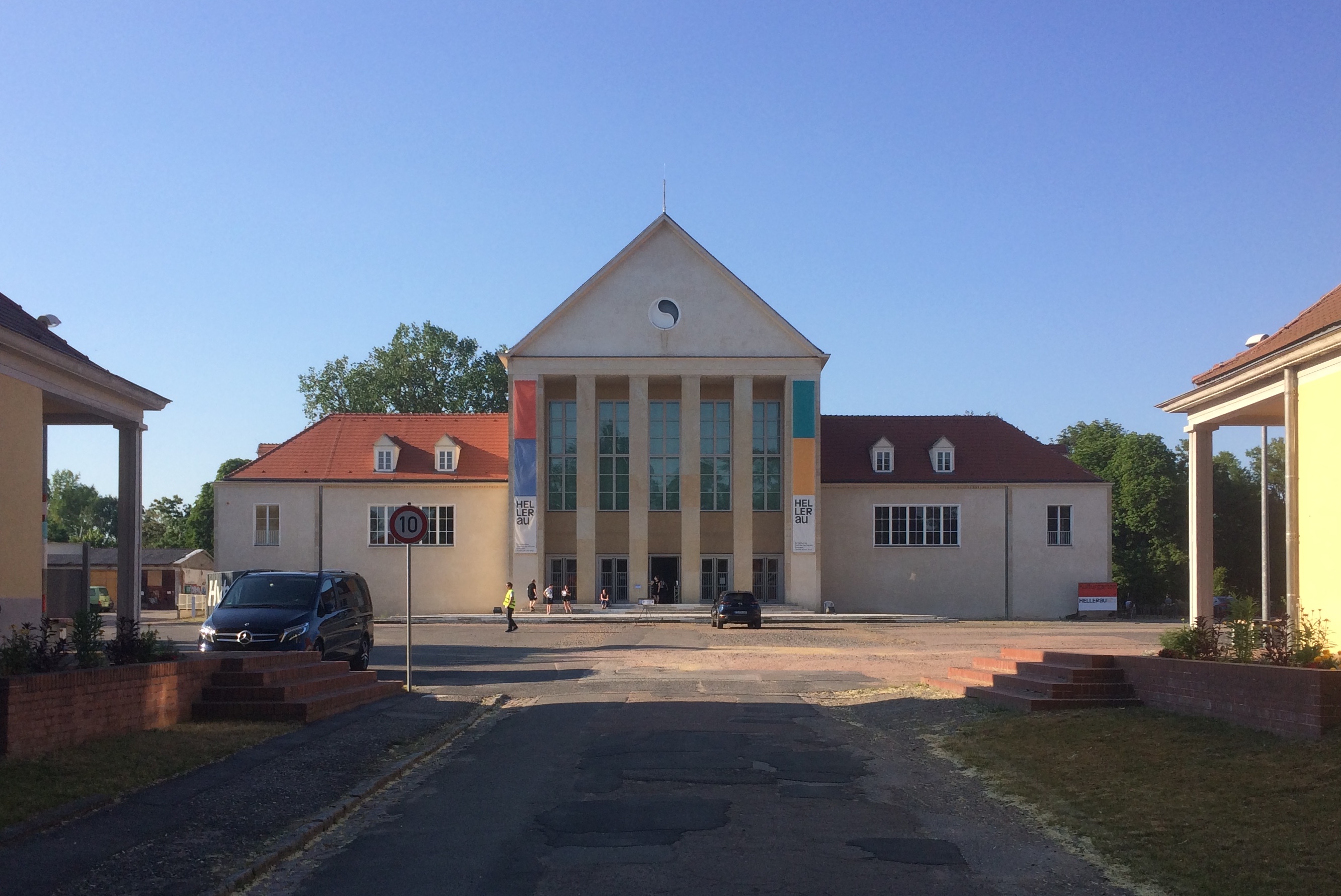 Ein kleines Theater mit Säulen in einer kleinen Straße unter blauem Himmel.