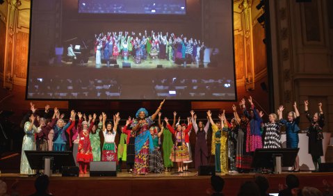 Frauen mit allen erdenklichen Hautfarben und Kleiderformen stehen als großer Chor zusammen auf der musicalwürdig beleuchteten Bühne.