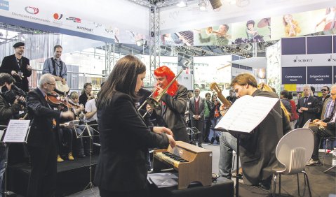 Euphorisch ins Messegeschäft gestartet: Susanne Kessel (am Toy Piano) leitete im Auftrag des Beethovenfestes Bonn eine Aufführung des MUSICIRCUS von John Cage am ConBrio-Messestand in der Mitte der Halle 3.1. Foto: David Kremser