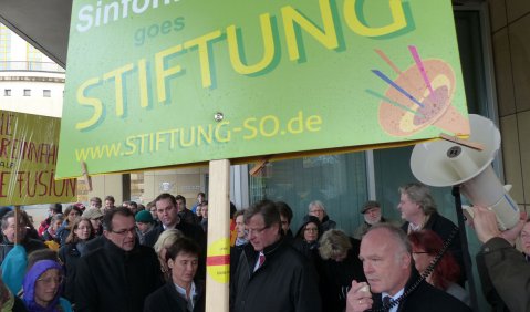 Vor der Ausschuss-Sitzung: SWR-Intendant und Fusionsinitiator Peter Boudgoust spricht zu den Demonstranten, Kabarettist und Fusionsgegner Matthias Deutschmann hält das Megaphon. Foto: Georg Rudiger