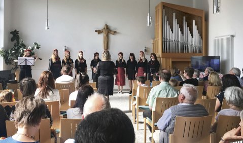 Ein kleines Vokalensemble mit Violinistin in einer gut besuchen Kirche.