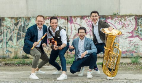 Vier Brüder in lockeren Anzügen mit verschiedenen Instrumenten wie Blockflöte, Geige und Tuba.