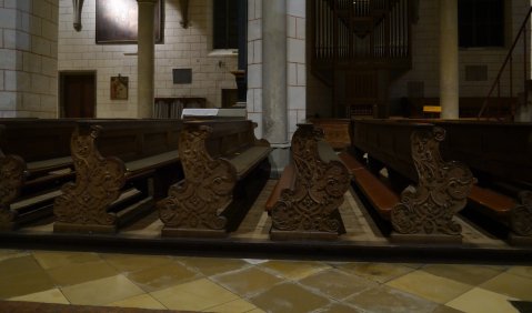 Dunkle Kirchenbänke in schwachem Licht.